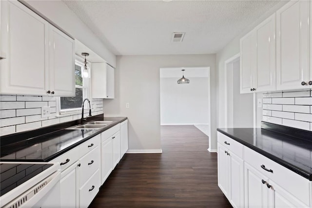1313 S Clark Ave, Independence, MO 64057 - kitchen with dark countertops, dark wood-style floors, white cabinets, backsplash, and a textured ceiling