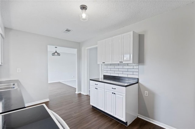 1313 S Clark Ave, Independence, MO 64057 - kitchen with white cabinetry, dark wood-style floors, backsplash, dark countertops, and a textured ceiling