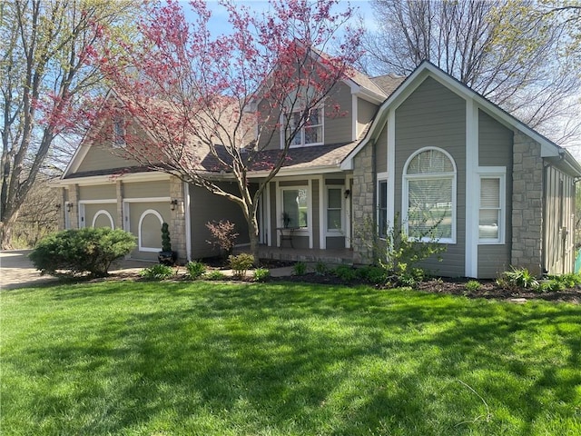 24445 E Truman Rd, Independence, MO 64056 - view of front of house featuring stone siding, a front yard, an attached garage, and covered porch