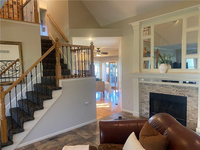 24445 E Truman Rd, Independence, MO 64056 - living area with a ceiling fan, stairs, a stone fireplace, stone tile flooring, and high vaulted ceiling