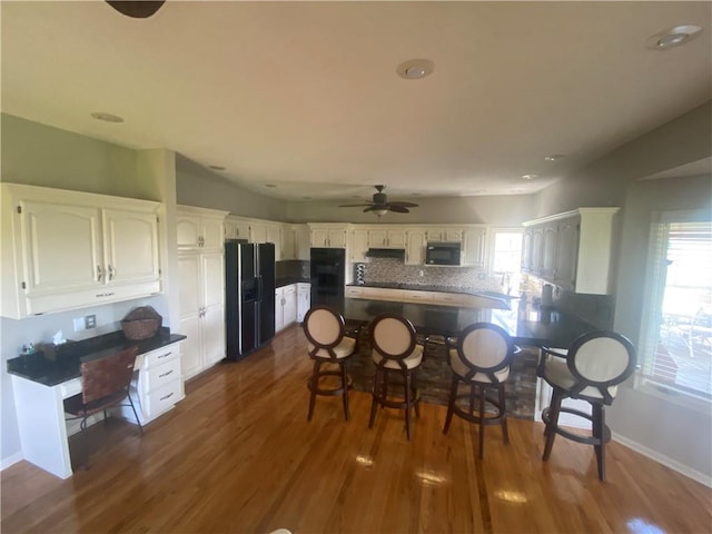 24445 E Truman Rd, Independence, MO 64056 - kitchen with black appliances, a peninsula, dark wood-type flooring, backsplash, and healthy amount of natural light