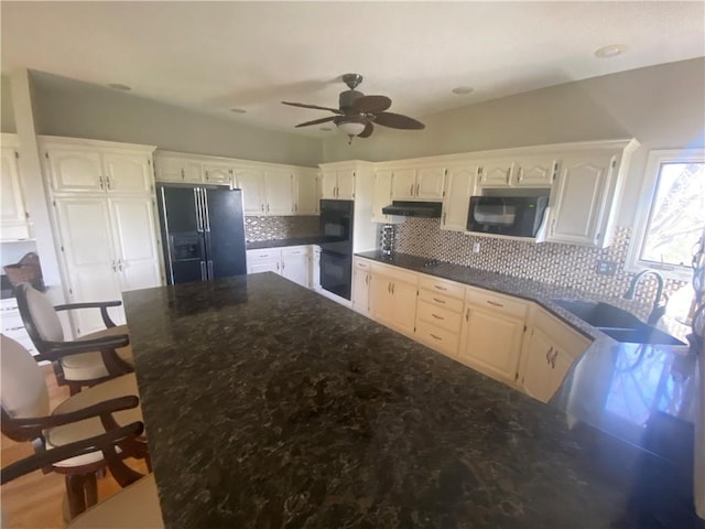 24445 E Truman Rd, Independence, MO 64056 - kitchen featuring black appliances, under cabinet range hood, ceiling fan, decorative backsplash, and white cabinetry