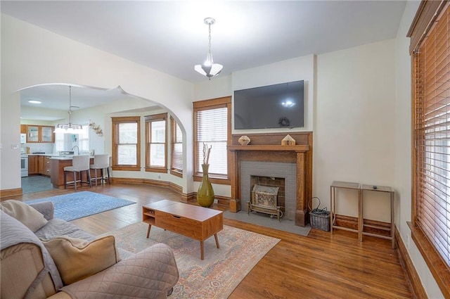 3923 Campbell St, Kansas City, MO 64110 - living room with arched walkways, wood finished floors, and healthy amount of natural light