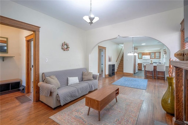 3923 Campbell St, Kansas City, MO 64110 - living room featuring arched walkways, stairs, and hardwood / wood-style flooring