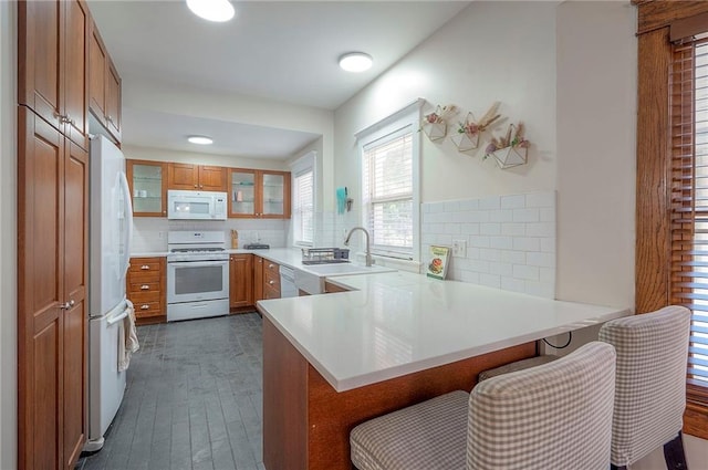3923 Campbell St, Kansas City, MO 64110 - kitchen with white appliances, brown cabinets, a peninsula, dark wood-style flooring, and glass insert cabinets