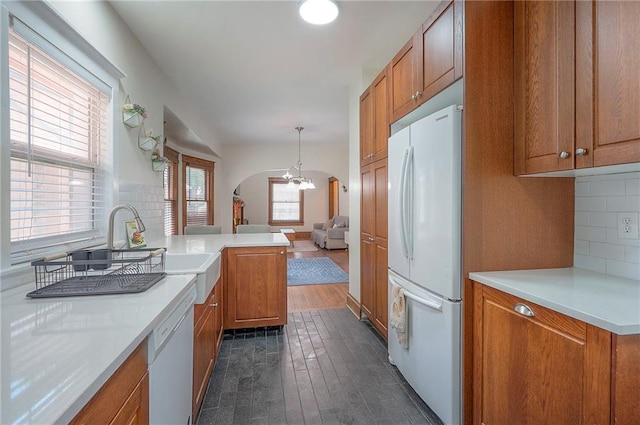 3923 Campbell St, Kansas City, MO 64110 - kitchen with white appliances, arched walkways, brown cabinets, and decorative backsplash