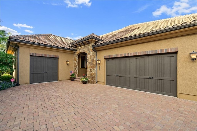 3116 W 137th St, Leawood, KS 66224 - mediterranean / spanish home featuring stucco siding, decorative driveway, stone siding, a tile roof, and a garage