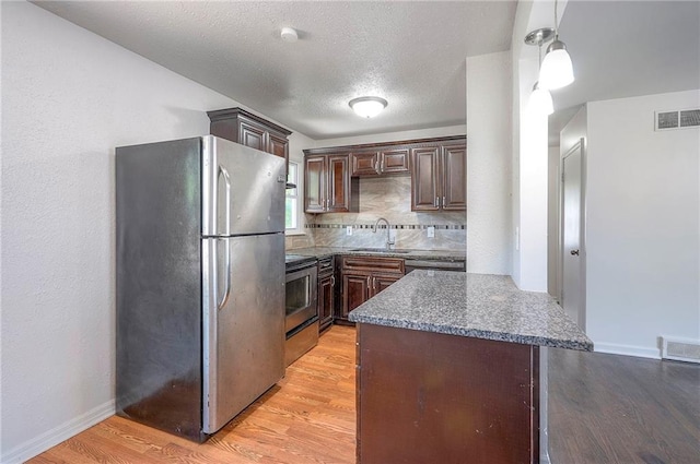 611 Pawnee Ln, Belton, MO 64012 - kitchen featuring appliances with stainless steel finishes, light wood-style flooring, dark brown cabinetry, pendant lighting, and a textured ceiling