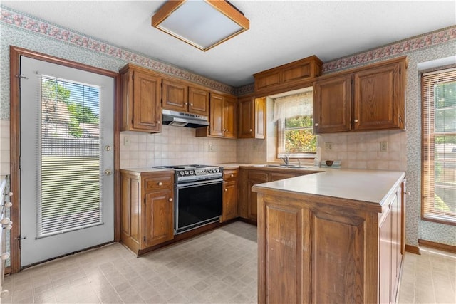 2117 Parker Ct, Blue Springs, MO 64015 - kitchen featuring stainless steel electric range, under cabinet range hood, wallpapered walls, light countertops, and a peninsula