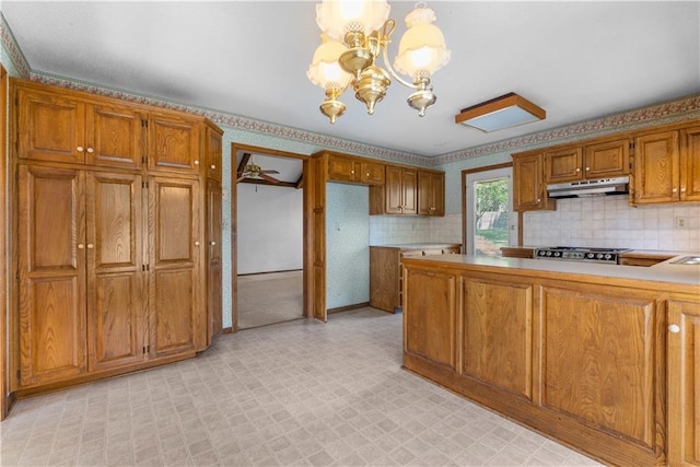 2117 Parker Ct, Blue Springs, MO 64015 - kitchen featuring under cabinet range hood, a chandelier, light flooring, brown cabinetry, and stainless steel gas stovetop