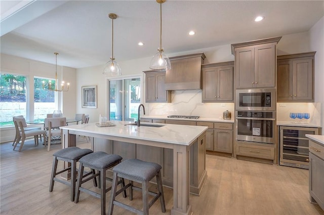 6753 Longview St, Shawnee, KS 66218 - kitchen featuring appliances with stainless steel finishes, beverage cooler, custom exhaust hood, light wood finished floors, and backsplash