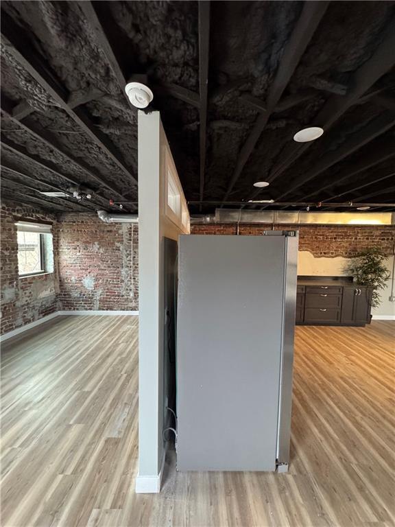 1018 Missouri Ave, Kansas City, MO 64106 - basement with brick wall, freestanding refrigerator, and light wood-type flooring