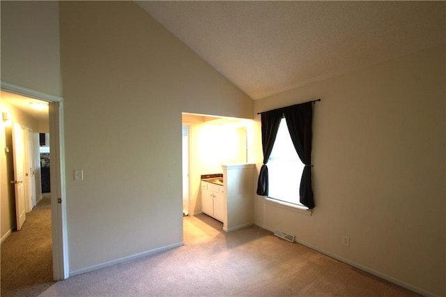 109 SE Rockwood St, Blue Springs, MO 64014 - unfurnished bedroom with light carpet, high vaulted ceiling, and connected bathroom