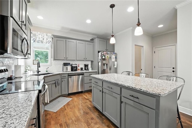 1016 SE Forest Ridge Ct, Blue Springs, MO 64014 - kitchen featuring appliances with stainless steel finishes, gray cabinets, ornamental molding, a kitchen breakfast bar, and tasteful backsplash