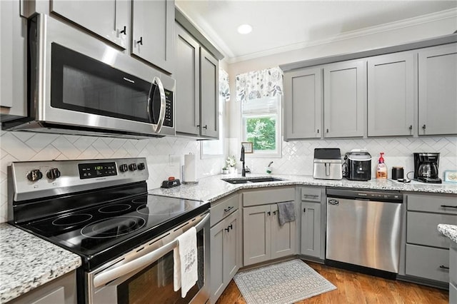 1016 SE Forest Ridge Ct, Blue Springs, MO 64014 - kitchen featuring appliances with stainless steel finishes, gray cabinets, crown molding, light wood-style floors, and tasteful backsplash