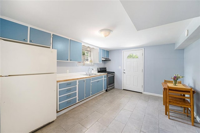 1806 E 125th St, Kansas City, MO 64146 - kitchen with freestanding refrigerator, blue cabinetry, stainless steel gas range oven, under cabinet range hood, and light countertops