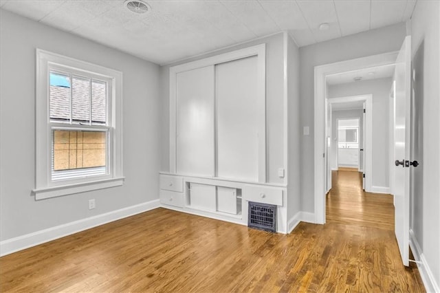 2647 Minnesota Ave, Kansas City, KS 66102 - unfurnished bedroom with wood finished floors, multiple windows, and a closet