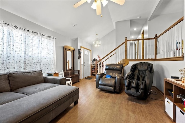 1005 Granada Dr, Raymore, MO 64083 - living area featuring wood finished floors, a ceiling fan, a chandelier, lofted ceiling, and stairs