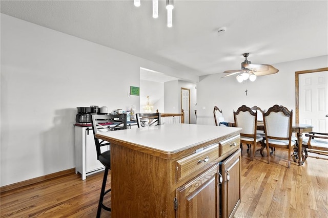 1005 Granada Dr, Raymore, MO 64083 - kitchen with ceiling fan, light wood-type flooring, a center island, a kitchen breakfast bar, and light countertops