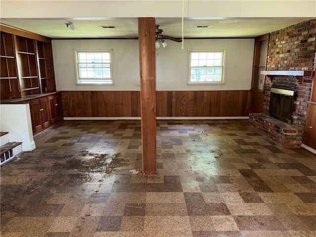 8812 W 72nd St, Overland Park, KS 66204 - unfurnished living room featuring a wainscoted wall, plenty of natural light, ceiling fan, a fireplace, and wood walls