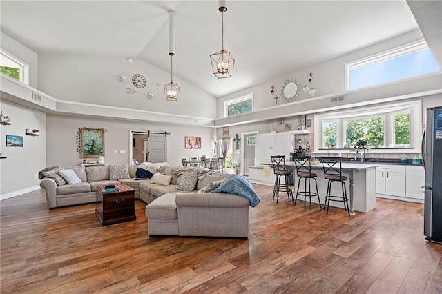 4815 Cheyenne Ln, Mclouth, KS 66054 - living area with high vaulted ceiling, hardwood / wood-style flooring, a barn door, plenty of natural light, and a chandelier