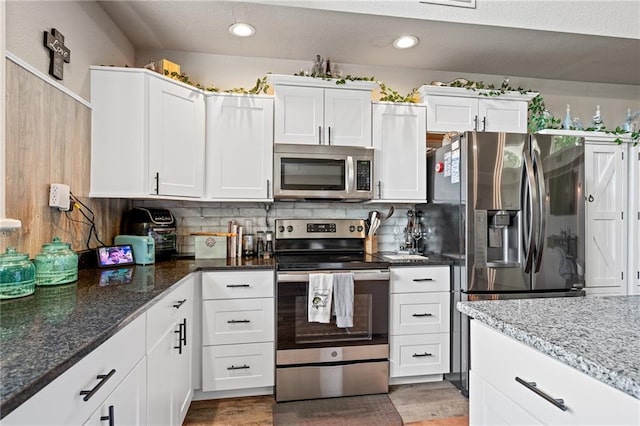 4815 Cheyenne Ln, Mclouth, KS 66054 - kitchen with stainless steel appliances, recessed lighting, white cabinetry, dark stone countertops, and decorative backsplash