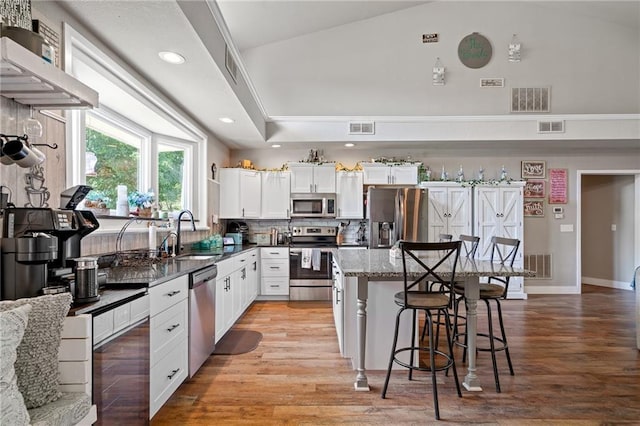 4815 Cheyenne Ln, Mclouth, KS 66054 - kitchen featuring appliances with stainless steel finishes, a breakfast bar area, white cabinetry, light wood-type flooring, and a kitchen island