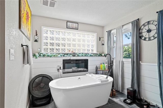 4815 Cheyenne Ln, Mclouth, KS 66054 - bathroom with a freestanding bath, a textured wall, a textured ceiling, and a wainscoted wall