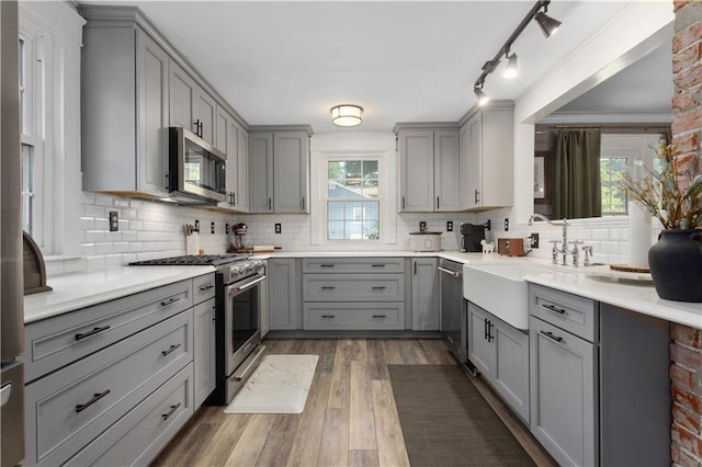 6000 Cherry St, Kansas City, MO 64110 - kitchen with gray cabinets, appliances with stainless steel finishes, backsplash, and wood finished floors