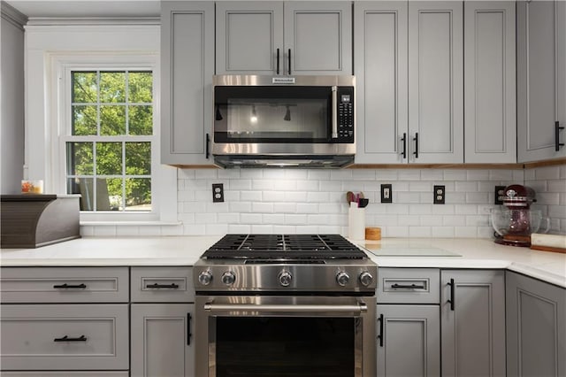 6000 Cherry St, Kansas City, MO 64110 - kitchen featuring appliances with stainless steel finishes, gray cabinetry, decorative backsplash, ornamental molding, and light stone countertops