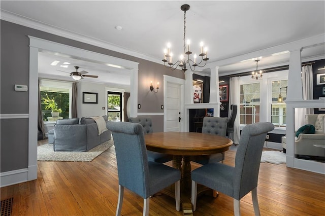 6000 Cherry St, Kansas City, MO 64110 - dining space with a chandelier, wood-type flooring, a fireplace, crown molding, and a ceiling fan