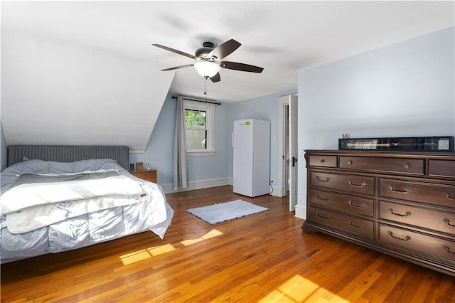 6000 Cherry St, Kansas City, MO 64110 - bedroom with wood finished floors, lofted ceiling, freestanding refrigerator, and a ceiling fan