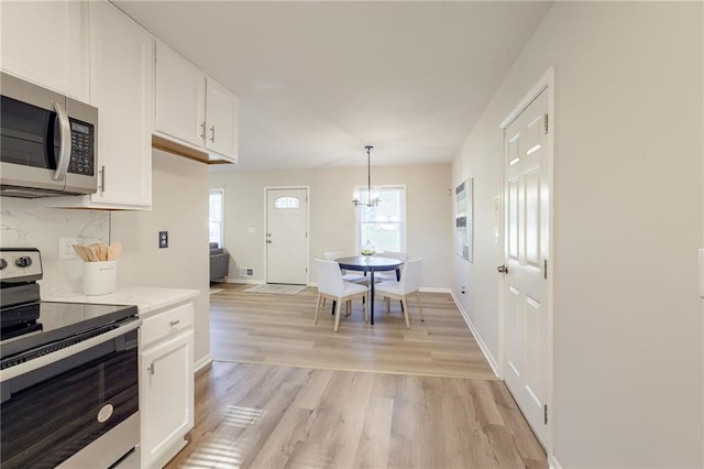 10201 Hillcrest Rd, Kansas City, MO 64134 - kitchen with appliances with stainless steel finishes, white cabinets, light wood-style floors, light countertops, and a chandelier