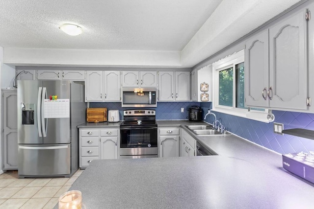 820 S Virginia Ln, Olathe, KS 66061 - kitchen featuring appliances with stainless steel finishes, backsplash, light tile patterned floors, a textured ceiling, and a peninsula