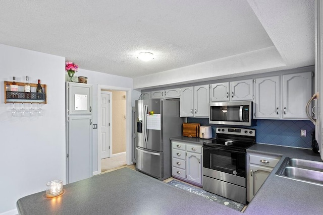 820 S Virginia Ln, Olathe, KS 66061 - kitchen with stainless steel appliances, dark countertops, backsplash, and a textured ceiling