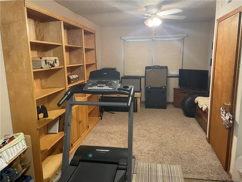 7609 Hayes St, Overland Park, KS 66204 - exercise area with a textured ceiling, ceiling fan, and carpet flooring