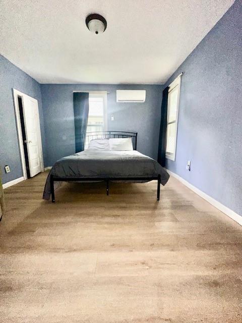 522 S 11th St, Independence, KS 67301 - bedroom featuring an AC wall unit, a textured ceiling, a textured wall, and wood finished floors