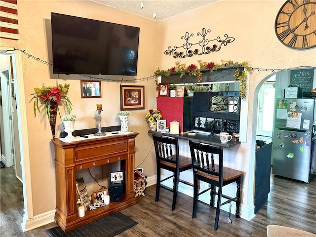 715 Harmon St, Saint Joseph, MO 64504 - bar featuring wood finished floors, freestanding refrigerator, arched walkways, and a textured ceiling