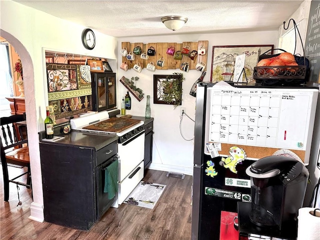 715 Harmon St, Saint Joseph, MO 64504 - kitchen with white range with gas stovetop, arched walkways, dark wood-style floors, dark cabinetry, and a textured ceiling