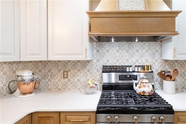 12408 Monroe Ave, Grandview, MO 64030 - kitchen featuring stainless steel range with gas cooktop, premium range hood, backsplash, and white cabinets