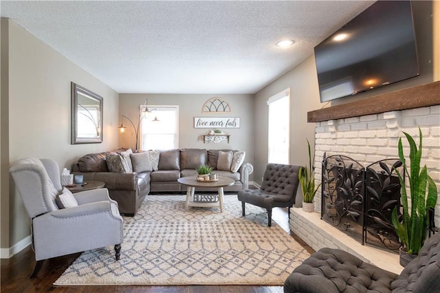 12408 Monroe Ave, Grandview, MO 64030 - living room featuring a textured ceiling, dark wood finished floors, and a brick fireplace