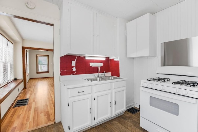 2527 N 18th St, Kansas City, KS 66104 - kitchen featuring gas range gas stove, wood finished floors, tasteful backsplash, light countertops, and white cabinets