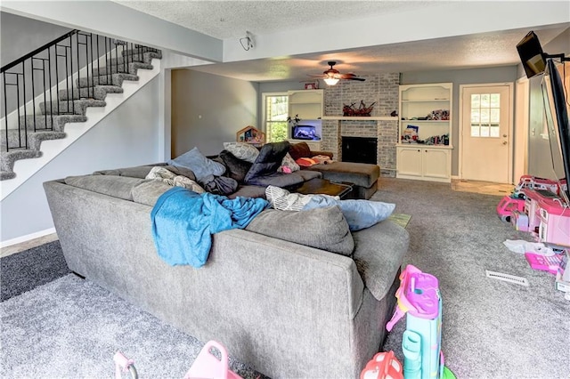 5300 NW 58th Ter, Kansas City, MO 64151 - carpeted living room featuring ceiling fan, a textured ceiling, healthy amount of natural light, stairway, and a brick fireplace