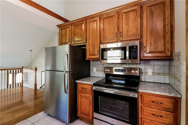 704 Canter St, Raymore, MO 64083 - kitchen with appliances with stainless steel finishes, brown cabinets, lofted ceiling, and backsplash