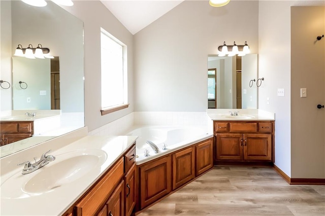 704 Canter St, Raymore, MO 64083 - bathroom featuring lofted ceiling, two vanities, wood finished floors, and a bath