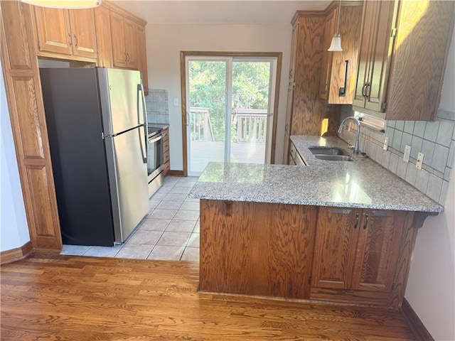 704 Canter St, Raymore, MO 64083 - kitchen with stainless steel appliances, light stone countertops, a peninsula, and decorative backsplash