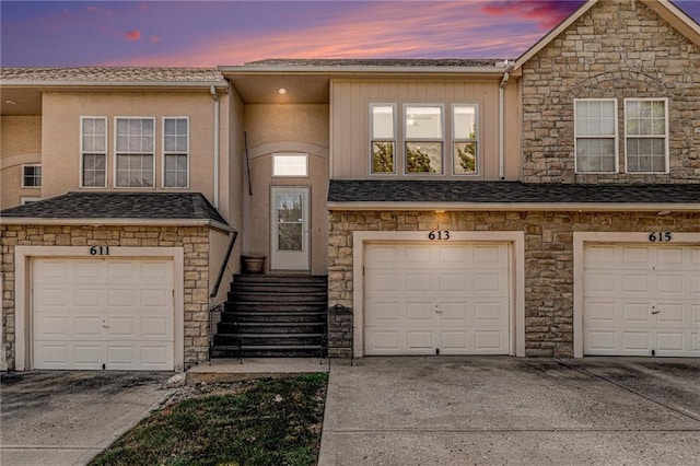 613 S Woodson Ln, Gardner, KS 66030 - view of front of house with stone siding, a garage, stucco siding, and concrete driveway