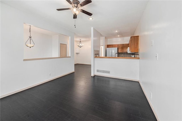 613 S Woodson Ln, Gardner, KS 66030 - unfurnished living room featuring ceiling fan, a chandelier, dark wood-style flooring, and recessed lighting