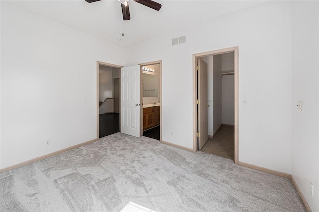 613 S Woodson Ln, Gardner, KS 66030 - unfurnished bedroom featuring a spacious closet, carpet, ensuite bath, and a ceiling fan