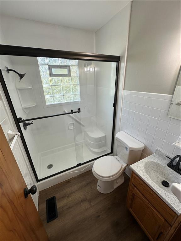 533 Utah St, Leavenworth, KS 66048 - bathroom with tile walls, wood finished floors, a stall shower, vanity, and a wainscoted wall